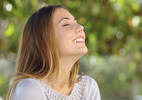 Smiling woman breathing fresh air through nose
