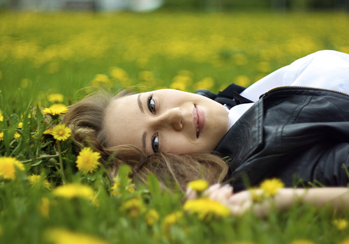 Woman Smiling laying on grass near flowers