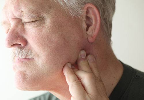 Older Gentleman holding jaw in pain